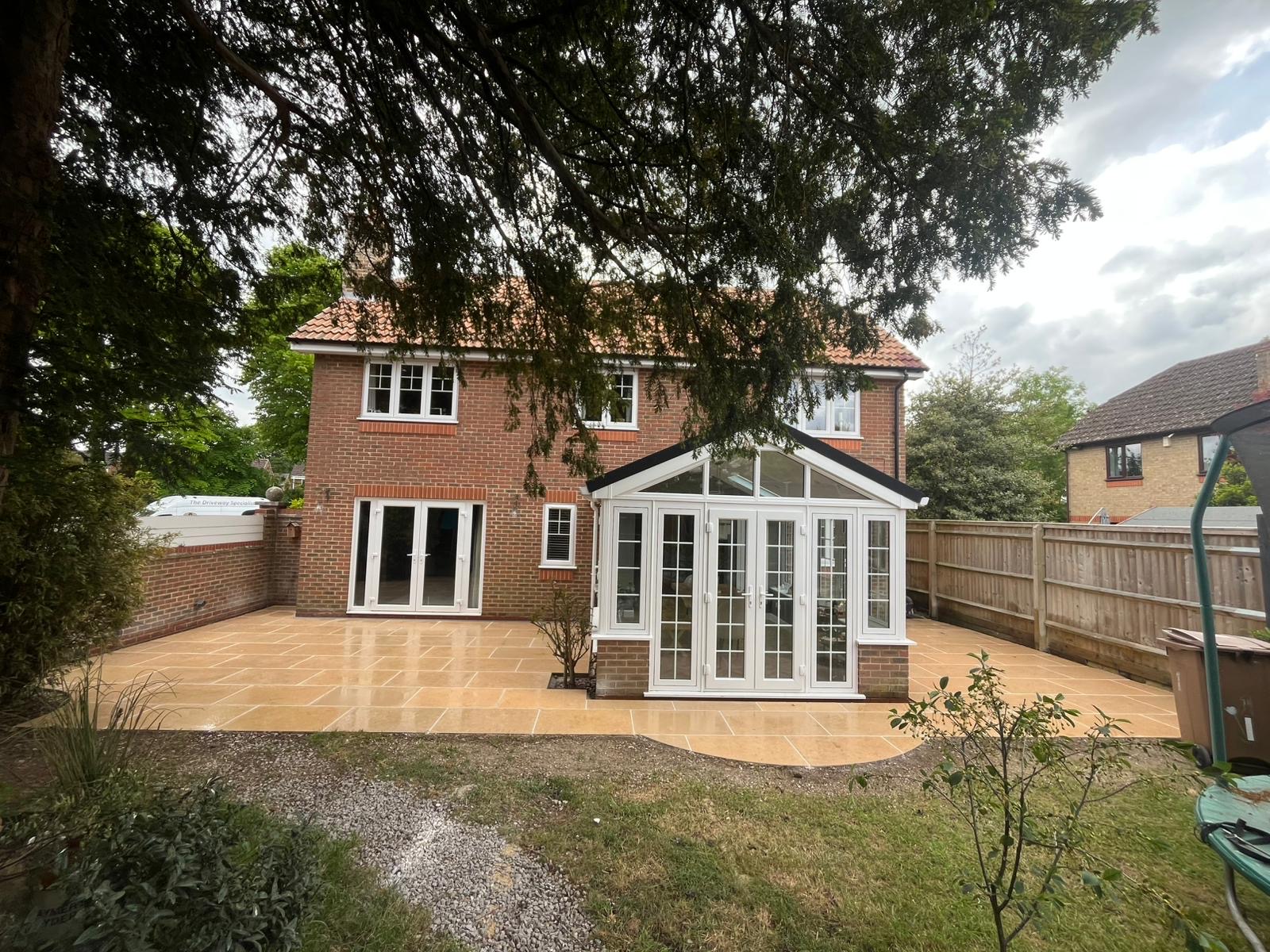 Indian sandstone patio behind a house with conservatory